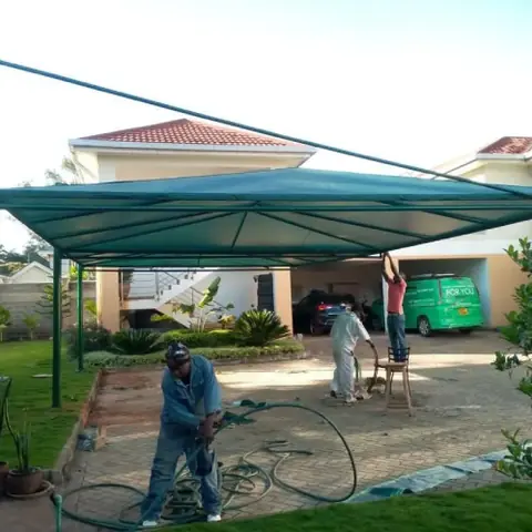 Green steel-framed car parking shade over a driveway
