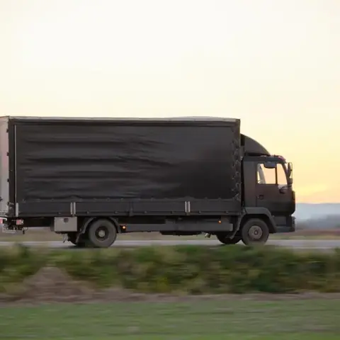 Cargo truck on a highway carrying tarpaulin-covered goods
